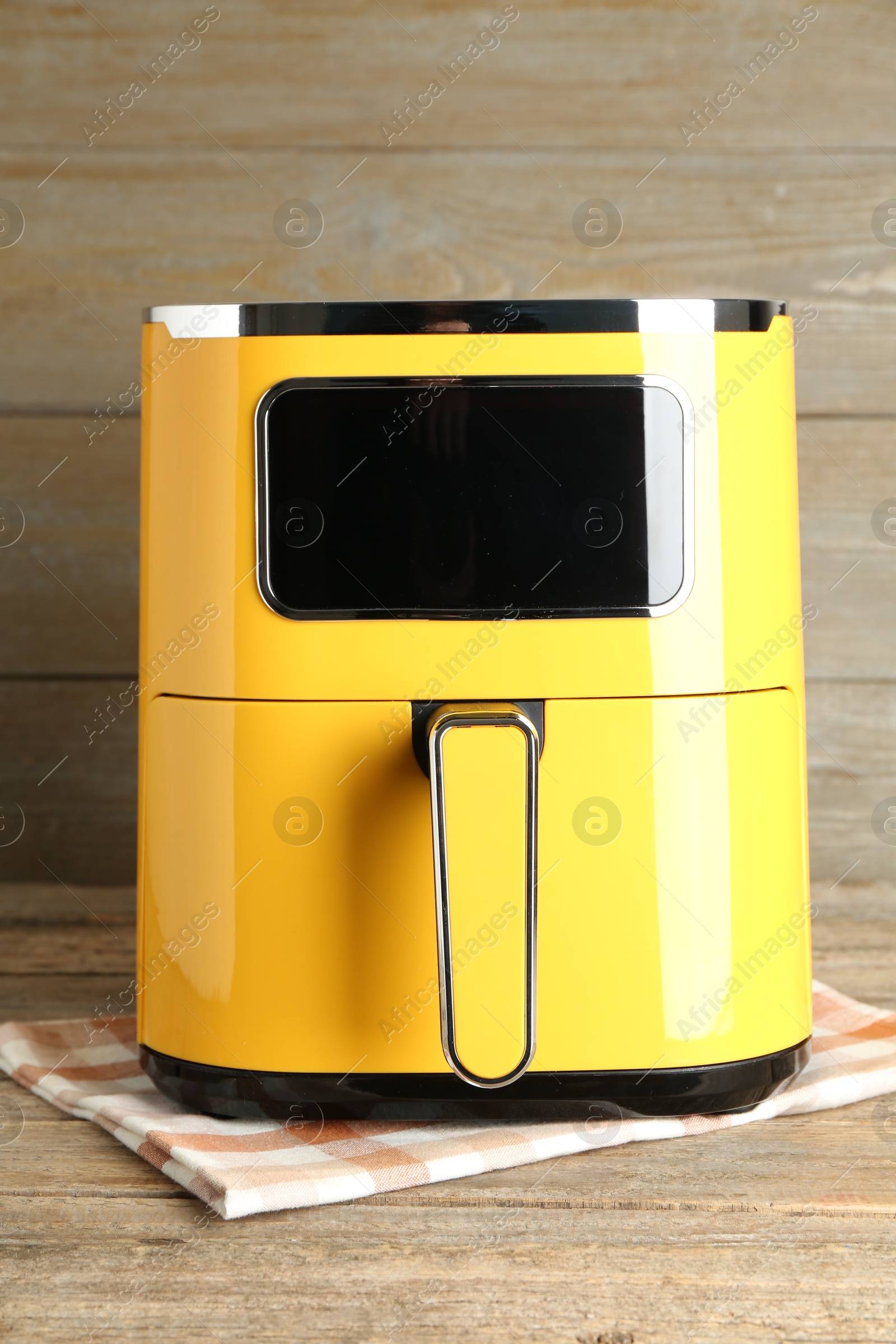 Photo of Yellow air fryer on wooden table. Modern kitchen appliance