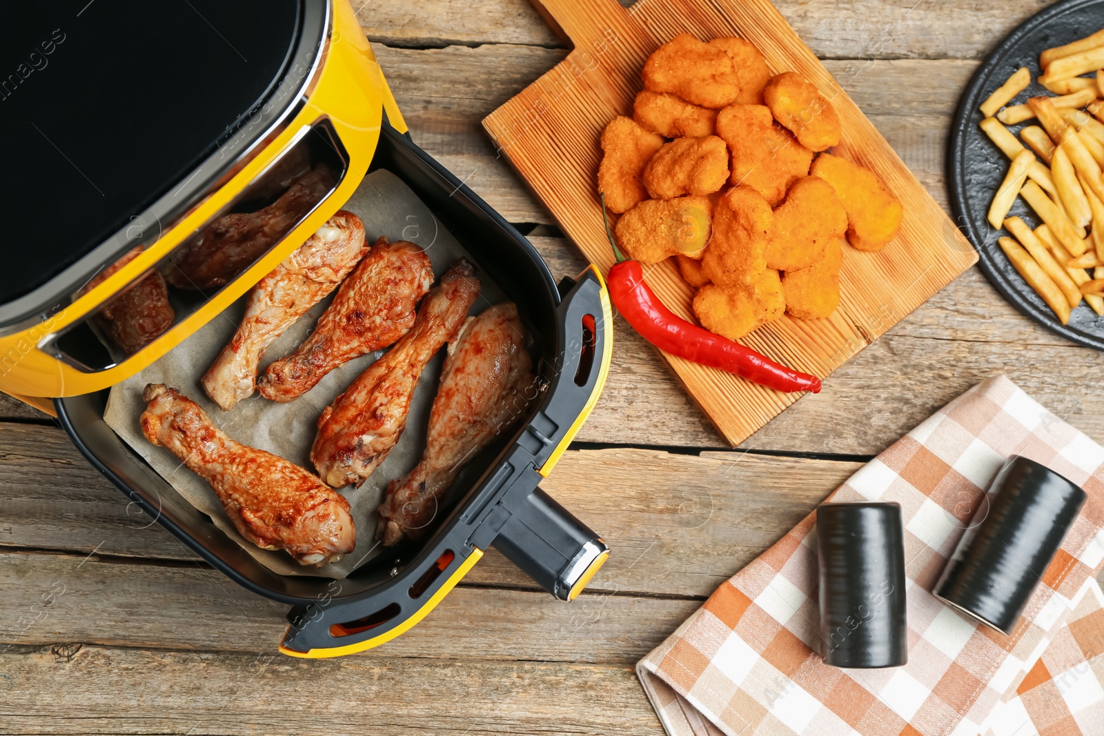 Photo of Modern air fryer and cooked meals on wooden table, flat lay