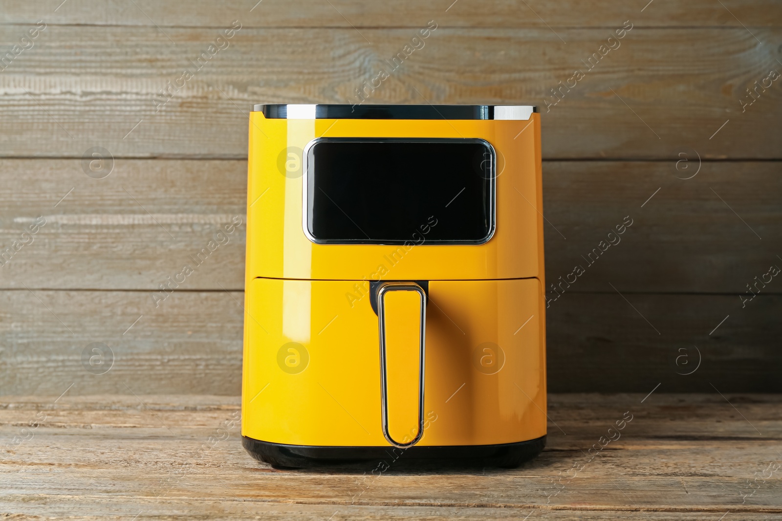 Photo of Yellow air fryer on wooden table. Modern kitchen appliance