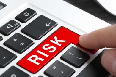 Image of Woman pressing red button with word Risk on keyboard, closeup