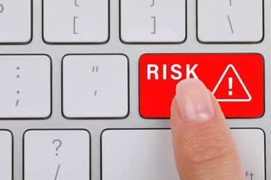 Image of Woman pressing red button with word Risk and warning sign on computer keyboard, closeup