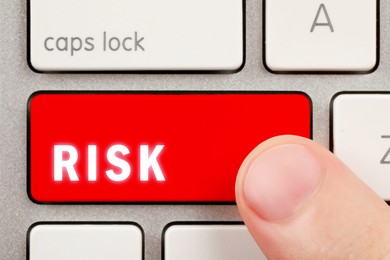 Image of Man pressing red button with word Risk on computer keyboard, top view