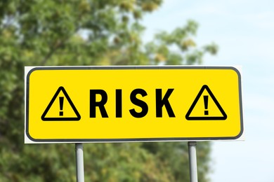 Image of Yellow road sign with word Risk and warning signs outdoors