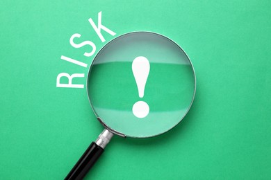 Image of Word Risk and magnifying glass above exclamation sign on green background, top view