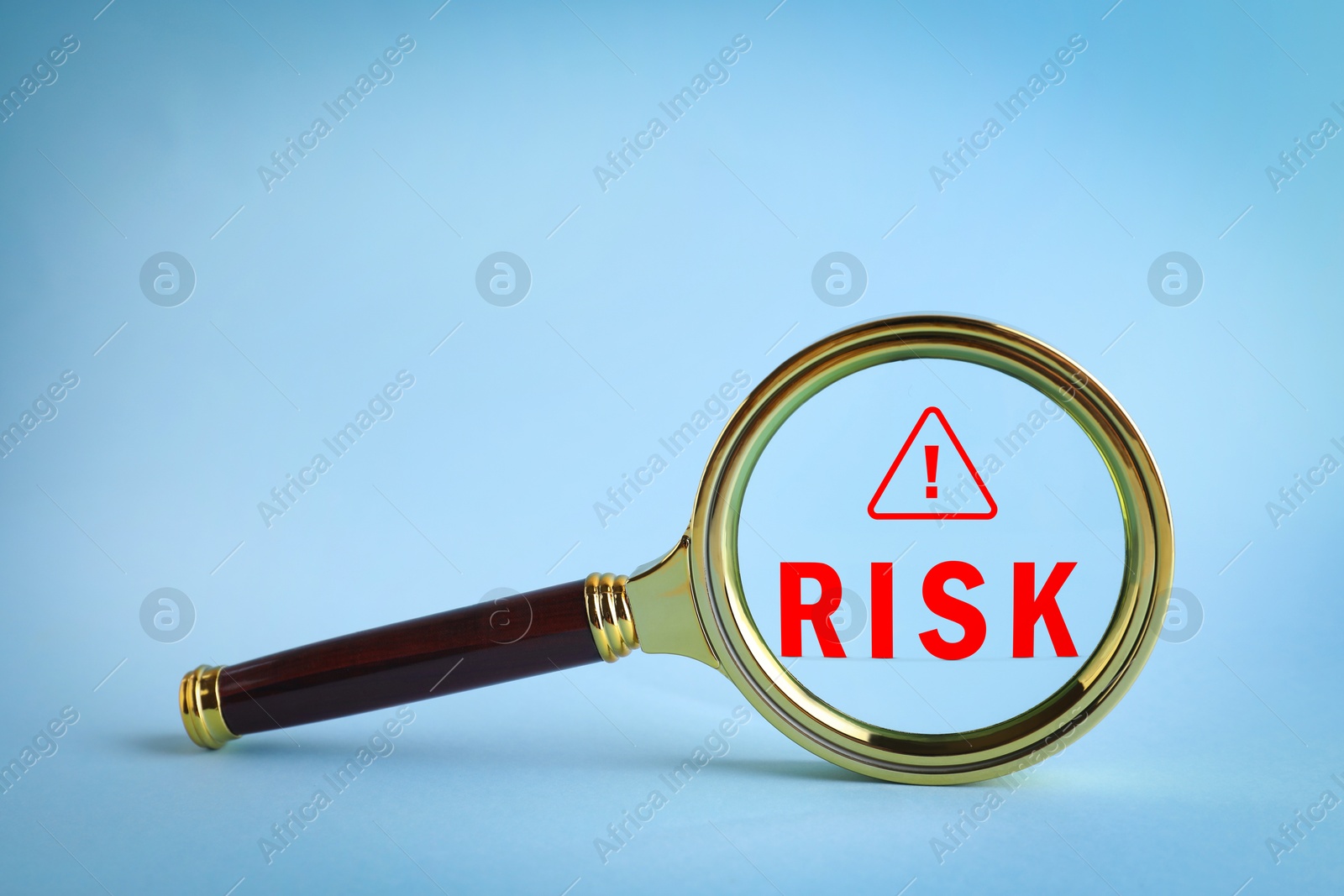 Magnifying glass with word Risk and warning sign inside against light blue background Image of Magnifying glass with word Risk and warning sign inside against light blue background