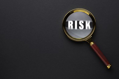 Image of Magnifying glass with word Risk inside on black background, top view