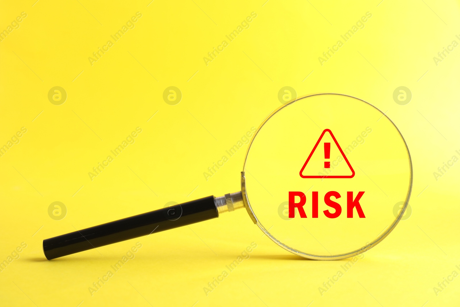 Image of Magnifying glass with word Risk and warning sign inside against yellow background