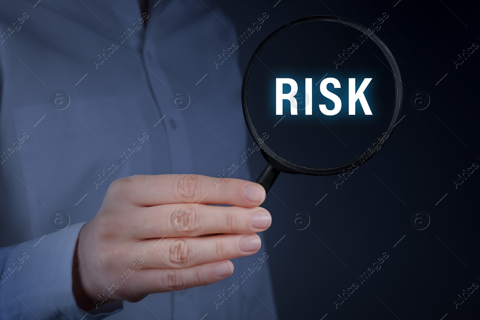 Image of Woman holding magnifying glass with word Risk inside against dark background, closeup