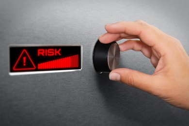 Image of Woman regulating level of risk using knob, closeup. Display with word and warning sign