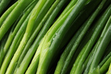 Photo of Fresh green spring onions with water drops as background, closeup