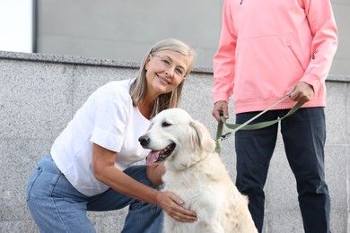 Photo of Senior couple with adorable Golden Retriever dog outdoors, closeup