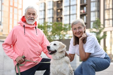 Photo of Portrait of happy senior couple with adorable Golden Retriever dog outdoors