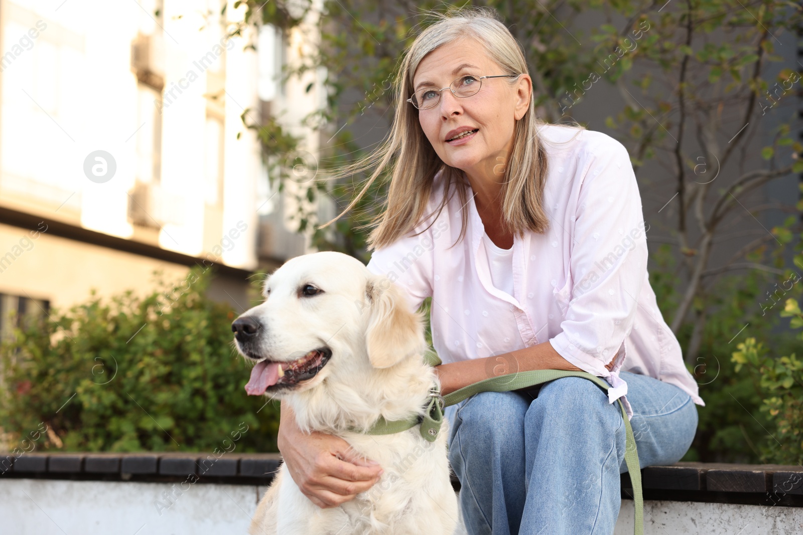 Photo of Senior woman with adorable Golden Retriever dog on bench outdoors. Space for text