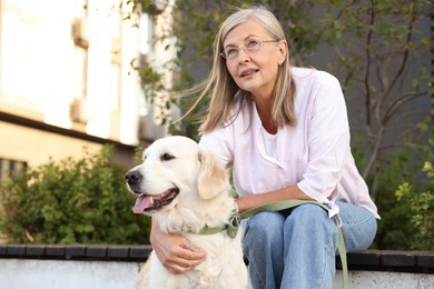 Photo of Senior woman with adorable Golden Retriever dog on bench outdoors. Space for text