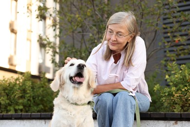 Photo of Senior woman with adorable Golden Retriever dog on bench outdoors