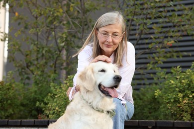 Photo of Senior woman with adorable Golden Retriever dog on bench outdoors