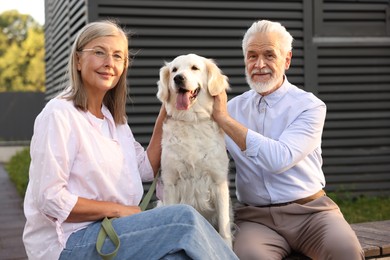 Photo of Happy senior couple with Golden Retriever dog outdoors