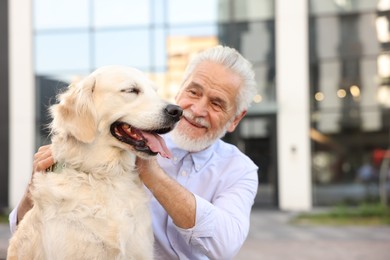 Photo of Smiling elderly man with adorable Golden Retriever dog outdoors. Space for text