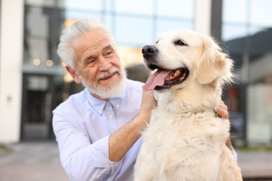 Photo of Smiling elderly man with adorable Golden Retriever dog outdoors