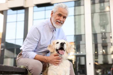 Photo of Portrait of elderly man with adorable Golden Retriever dog on bench outdoors, low angle view. Space for text