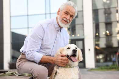 Photo of Portrait of elderly man with adorable Golden Retriever dog on bench outdoors. Space for text