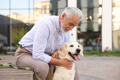 Photo of Elderly man with adorable Golden Retriever dog on bench outdoors. Space for text