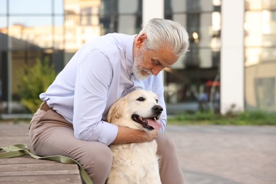 Photo of Elderly man with adorable Golden Retriever dog on bench outdoors. Space for text