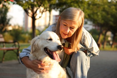Photo of Senior woman with adorable Golden Retriever dog outdoors