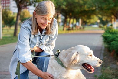 Photo of Senior woman with adorable Golden Retriever dog outdoors