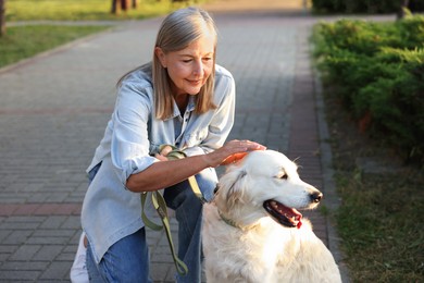 Photo of Senior woman with adorable Golden Retriever dog outdoors