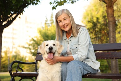 Photo of Portrait of smiling senior woman with adorable Golden Retriever dog on bench outdoors