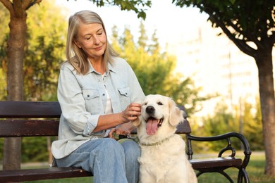 Photo of Senior woman with adorable Golden Retriever dog on bench outdoors