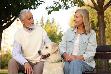 Photo of Senior couple with adorable Golden Retriever dog on bench outdoors