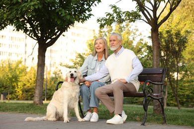 Photo of Senior couple with adorable Golden Retriever dog on bench outdoors