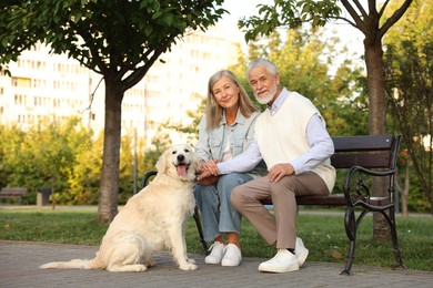 Photo of Senior couple with adorable Golden Retriever dog on bench outdoors