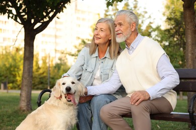 Photo of Happy senior couple with adorable Golden Retriever dog on bench outdoors
