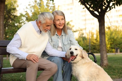 Photo of Happy senior couple with adorable Golden Retriever dog on bench outdoors