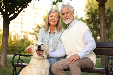 Photo of Portrait of happy senior couple with adorable Golden Retriever dog on bench outdoors