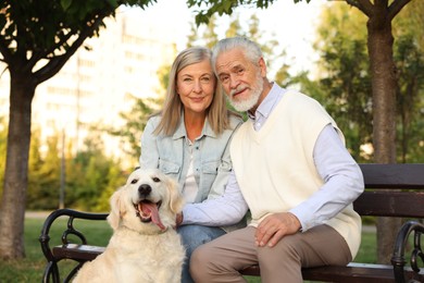 Photo of Portrait of happy senior couple with adorable Golden Retriever dog on bench outdoors