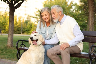 Photo of Happy senior couple with adorable Golden Retriever dog on bench outdoors