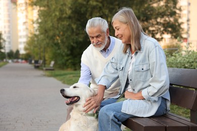 Photo of Senior couple with adorable Golden Retriever dog on bench outdoors. Space for text