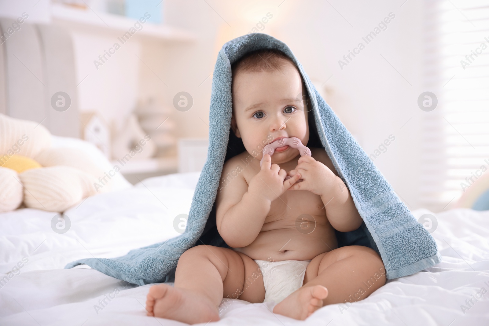 Photo of Cute baby wrapped with blue towel after bathing on bed at home