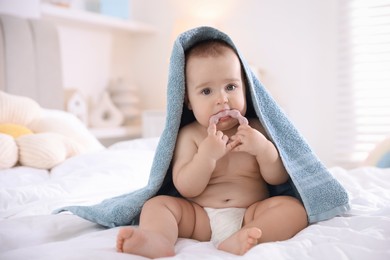Photo of Cute baby wrapped with blue towel after bathing on bed at home