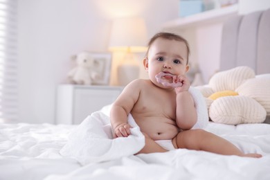Photo of Cute baby with white towel and teether after bathing on bed at home, space for text