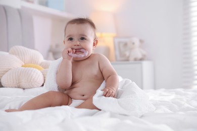 Photo of Cute baby with white towel and teether after bathing on bed at home, space for text