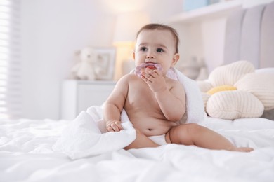 Photo of Cute baby with white towel and teether after bathing on bed at home