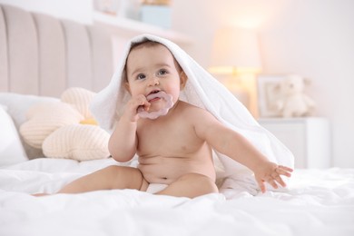 Photo of Cute baby with white towel and teether after bathing on bed at home