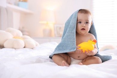Photo of Cute baby wrapped with blue towel after bathing on bed at home, space for text