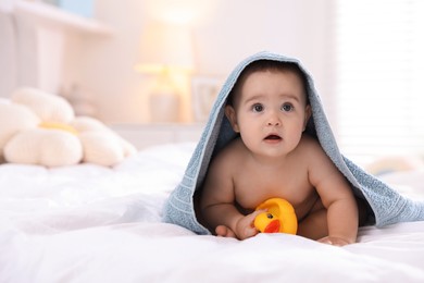 Photo of Cute baby wrapped with blue towel after bathing on bed at home, space for text