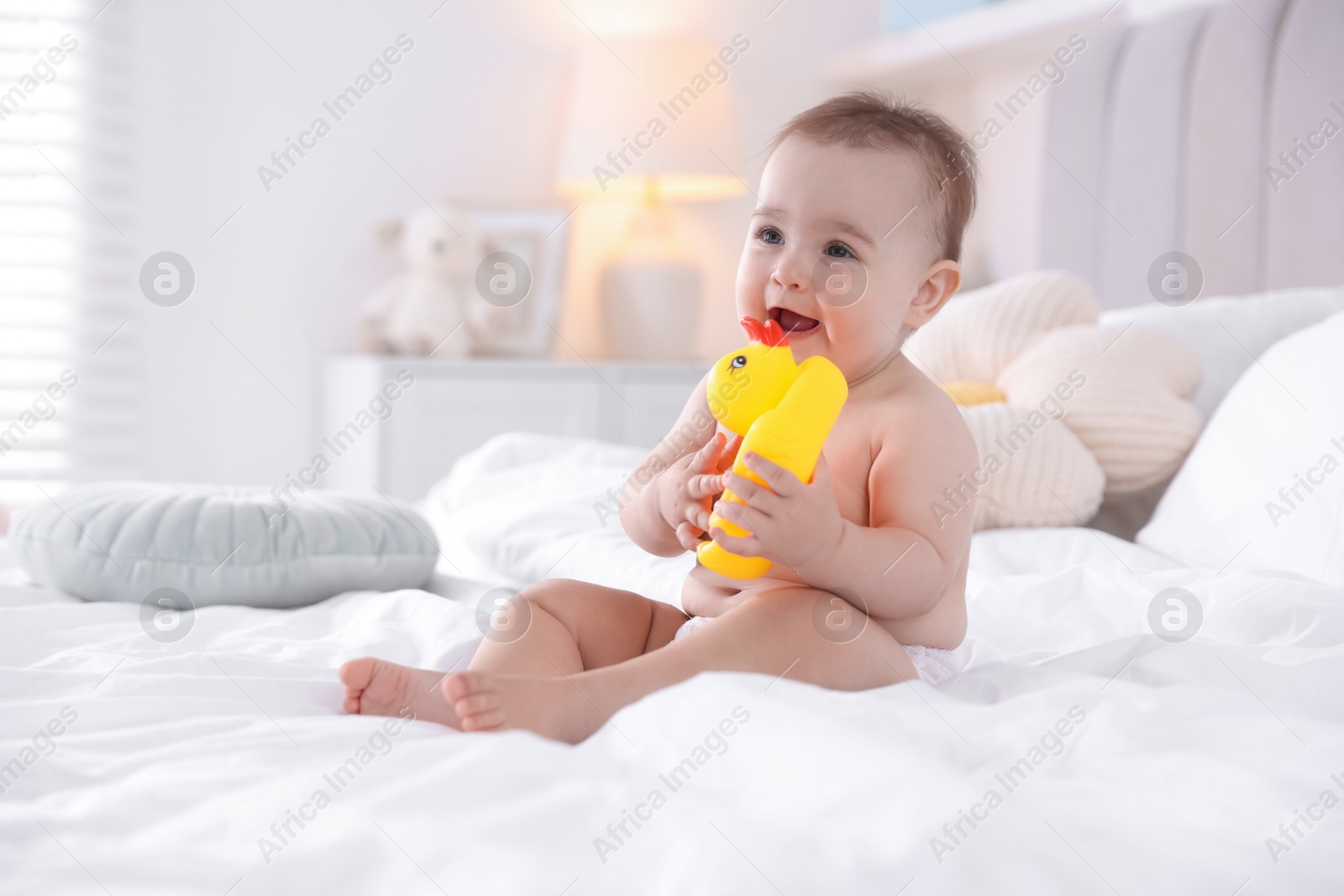 Photo of Cute baby with rubber duck after bathing on bed at home